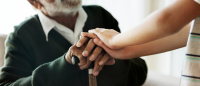 Young person holding hands with elderly man.